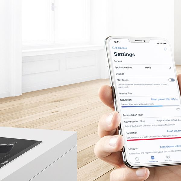 A aplicação Home Connect num smartphone. Uma placa inteligente com uma frigideira no fundo.