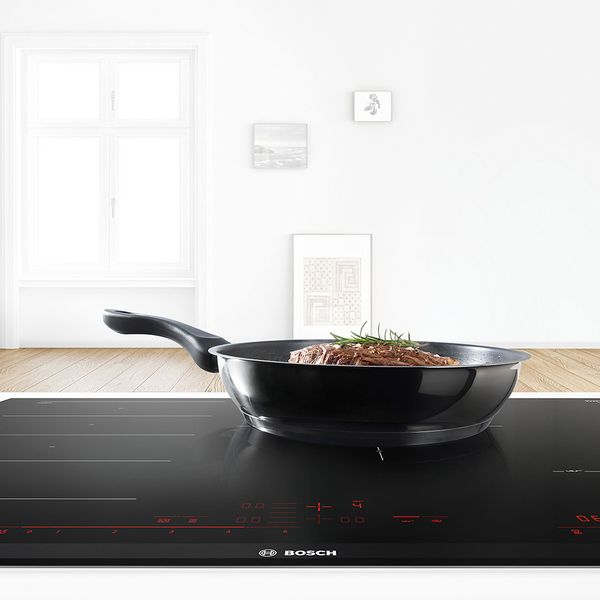 Une table de cuisson avec une poêle dans laquelle cuit un steak