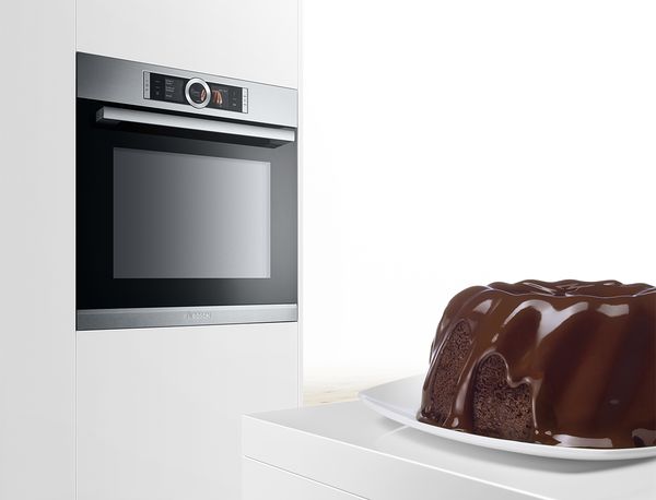Torta al cioccolato davanti a un forno Bosch in una cucina bianca dallo stile moderno.