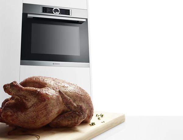 A chicken roasting in an oven with a meat probe monitoring the temperature.