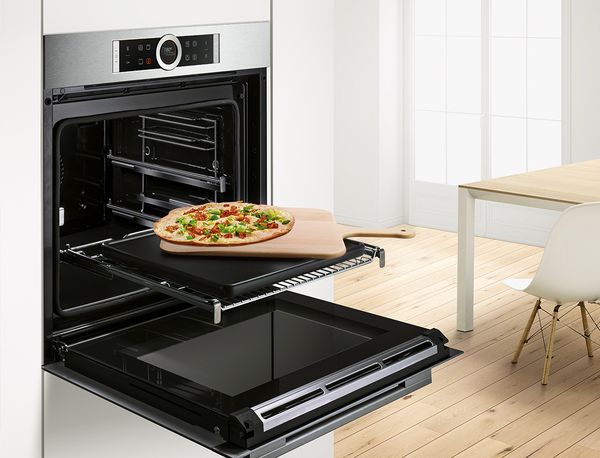 A Bosch oven with an open door showing a homemade pizza.