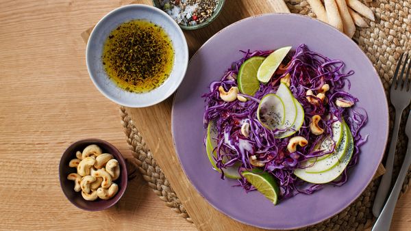 Fresh purple cabbage and green apple salad, garnished with cashews.