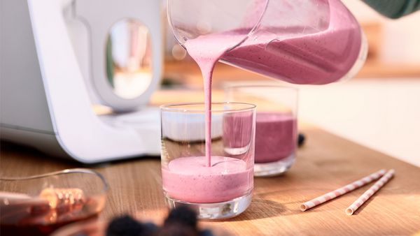 A strawberry smoothie being poured into a glass.