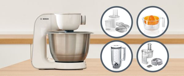 Bosch Küchenmaschine in weiß mit Edelstahlschüssel und vier verschiedenen Zubehörteilen.