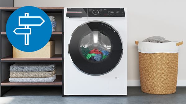 Prikaz belega pralnega stroja z digitalnim zaslonom na dotik od blizu in otroška sobica v ozadju.