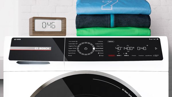 Küchenwecker neben einer Bosch Waschmaschine, eingestellt auf die Dauer eines 45-minütigen Schnellwaschprogramms.