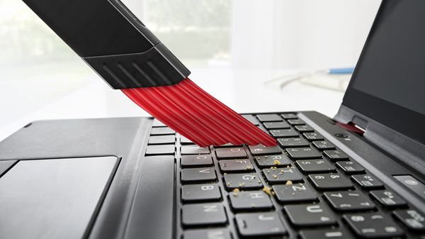 Eine Laptoptastatur wird mit dem Bosch Unlimited Akku-Staubsauger gereinigt.