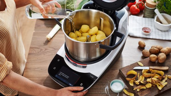 Eine Familienportion geschälter roher Kartoffeln im Cookit, der Benutzer gibt Wasser zum Kochen hinzu.   