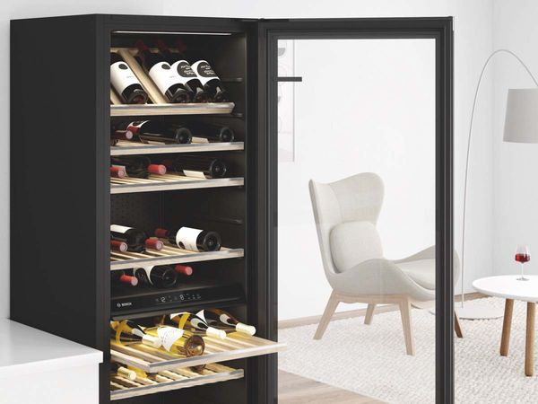Élégante cave à vin pose-libre avec une porte ouverte présentant six étagères coulissantes en bois, un éclairage LED.