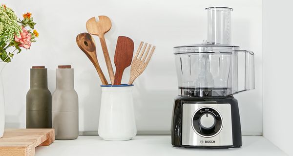 Un robot de cocina colocado junto a los utensilios, la sal y la pimienta en una encimera.