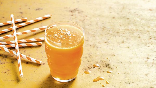 Žuti sok od različitog voća i povrća u čaši.
