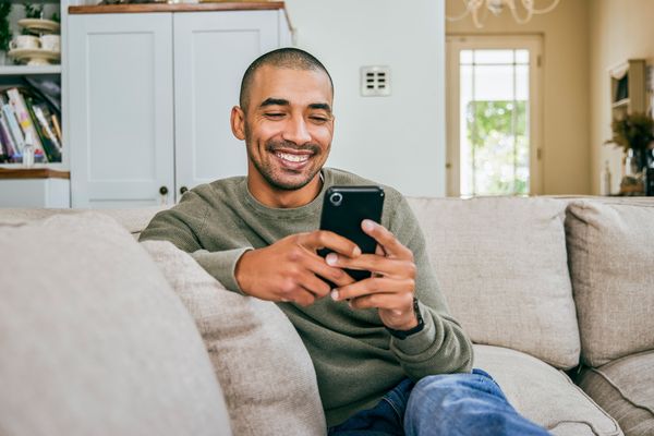 Uomo che utilizza uno smartphone per controllare gli elettrodomestici smart da remoto