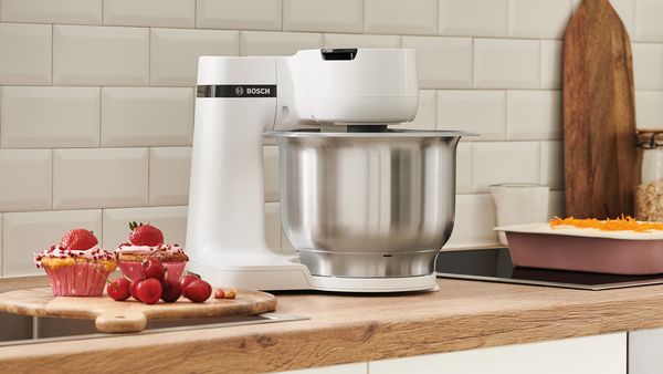 Auf einer Küchenarbeitsplatte befindet sich eine weiße Bosch Küchenmaschine mit großer Rührschüssel aus Edelstahl.