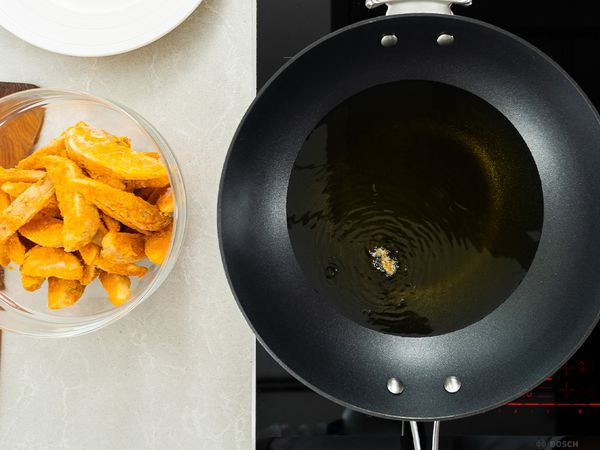 9. Into a heated frying pan, bring cooking oil up to temperature. Test with one potato wedge. The oil is hot if bubbles form. Add all potato wedges and fry for about 5 to 8 minutes until golden.