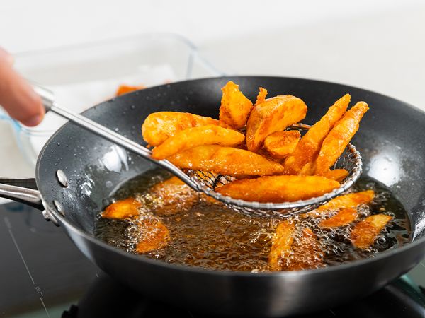 9. Into a heated frying pan, bring cooking oil up to temperature. Test with one potato wedge. The oil is hot if bubbles form. Add all potato wedges and fry for about 5 to 8 minutes until golden.