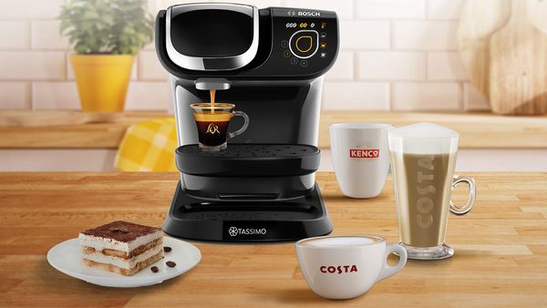 Tassimo coffee machine surrounded by cake and different coffees