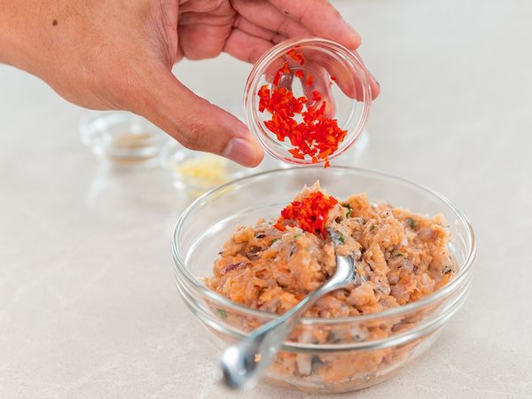 4. Empty blended paste into a bowl. Add chopped Thai chilli, 1 tablespoon of chopped garlic, 2 tablespoons of chopped shallots, salt and pepper. Mix well to combine.