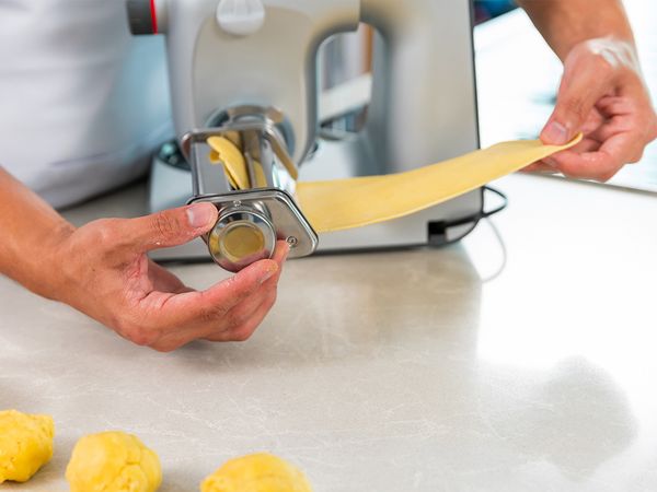 5. Remove dough from fridge and cling film. Split dough into 8 portions. Attach Pasta Press Attachment to your Kitchen Machine. Turn on at Speed 3. Start Pasta Attachment at Thickness Level 8. Pass each portion through Pasta Press. Fold into a third and repeat pasta pressing with decreasing thickness level each time until 0.