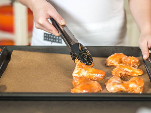 Adding marinated chicken wings to a pan