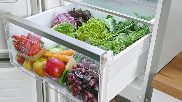 Dwie szuflady VitaFresh w chłodziarce z kontrolą wilgotności oraz miejscem do przechowywania o temperaturze 0°C wypełnione owocami, warzywami i mięsem.