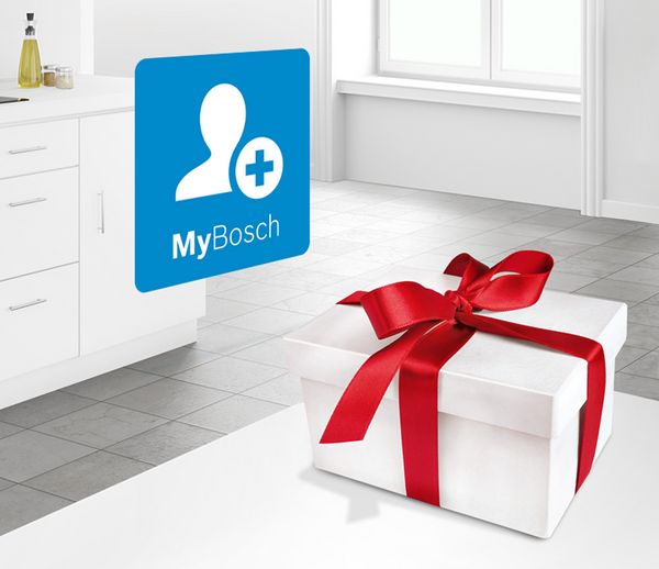 Eine weiße Geschenkbox mit rotem Band liegt auf einem Küchenboden, im Hintergrund ist das MyBosch-Logo sichtbar. 