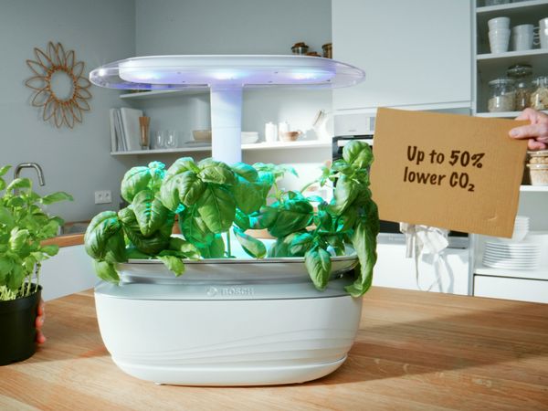 SmartGrow Life sitting on kitchen table with cardboard sign saying up to 50% less CO2.