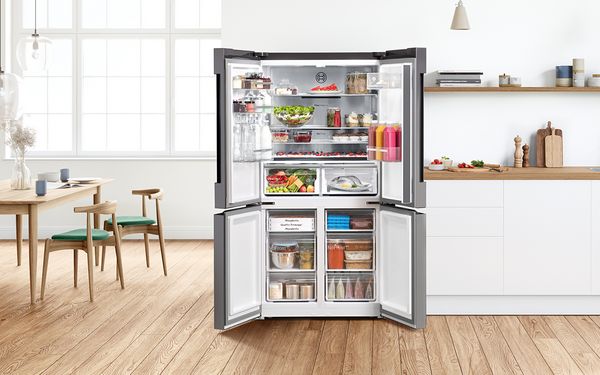 The doors of the French Door fridge are open and the fridge is filled with fresh groceries.