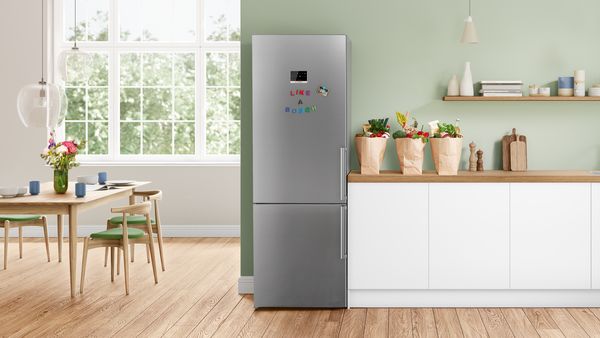 Az extra nagyméretű Bosch hűtő-fagyasztó egy konyhában a falnál áll, egy bevásárlótáskával a konyhaszigeten.