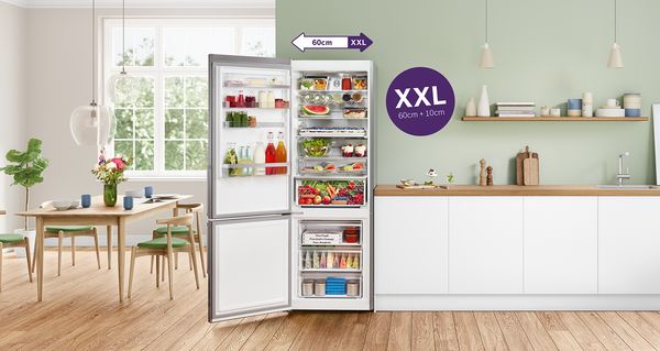 „Bosch“ itin didelis šaldytuvas su šaldikliu atidarytomis durimis virtuvės aplinkoje. Jame pilna šviežių maisto produktų. 