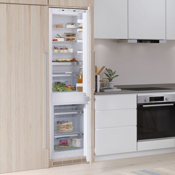 Light kitchen with integrated built in Bosch Fridge Freezer open showing inside contents