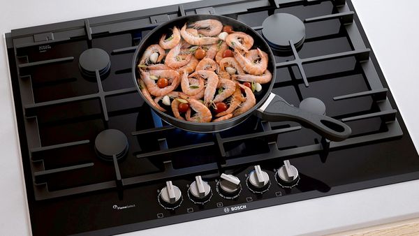 Shrimp cooking in a pan on a gas hob.