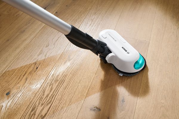 Testina di una scopa elettrica Bosch in funzione mentre pulisce un pavimento in legno