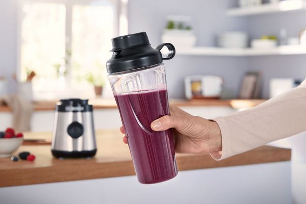 A woman holding the Bosch Miniblender VitaPower Series 2 filled with a smoothie in her hand.