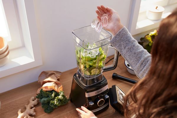 A women putting ice cubes in the Bosch blender VitaBoost Series 6 to make a smoothie.