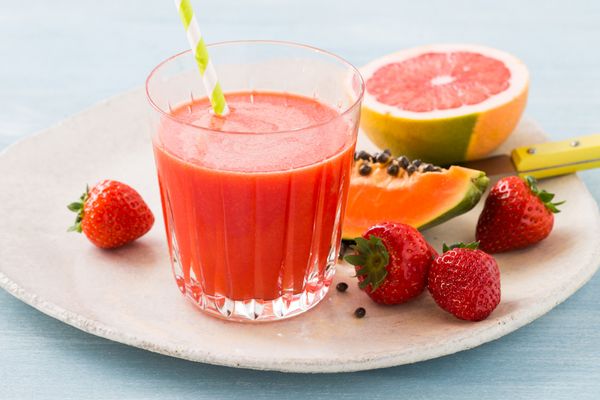 Un delicioso zumo rojo en un plato con frutas frescas.