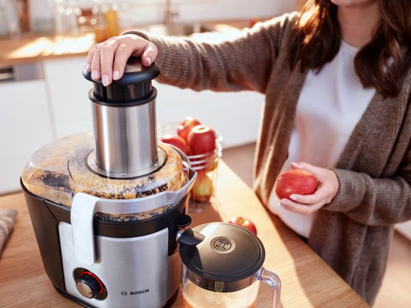 A woman grabs an apple to make fresh juice with the Bosch centrifugal juicer VitaJuice.