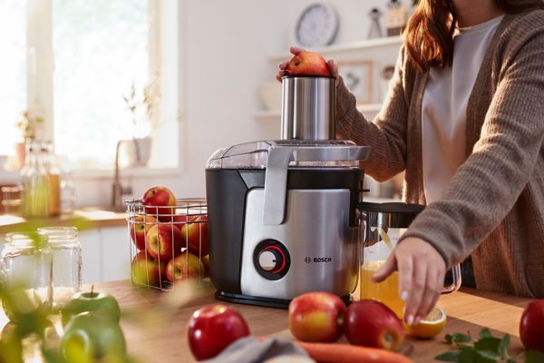 A woman making fresh juice with the BOSCH centrifugal juicer VitaJuice.