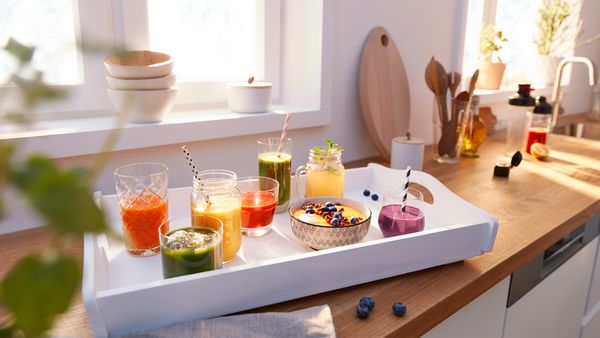 Different smoothies standing on a tablet in the kitchen.