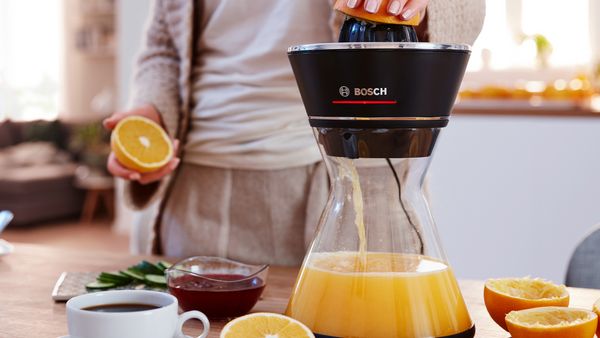 Os espremedores de citrinos VitaStyle da Bosch com um jarro de vidro numa bancada de cozinha.