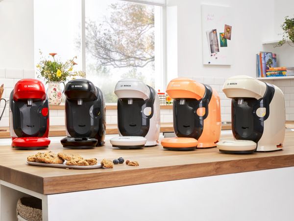 Different colours of the TASSIMO STYLE coffee machine on a kitchen worktop.