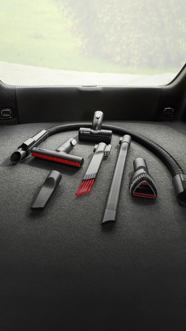 Zubehör-Set für deinen Akku-Staubsauger im Kofferraum eines Autos. Verschiedene Düsen, Bürsten und Schläuche.