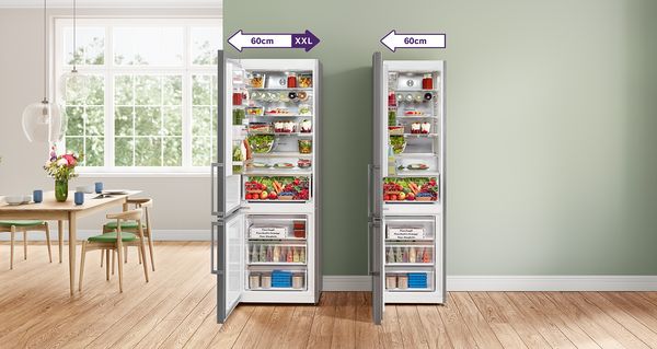 Egy nagyméretű nyitott 70 cm-es hűtő-fagyasztó egy szabadon álló, 60 cm-es hűtő-fagyasztó mellett. Mindkettő friss élelmiszerekkel van feltöltve.