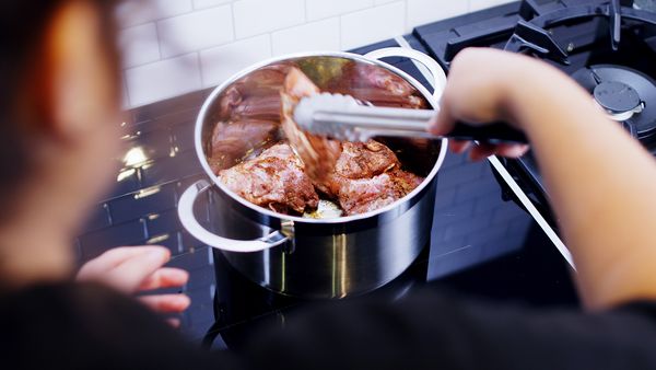Person cooking chicken in a pan