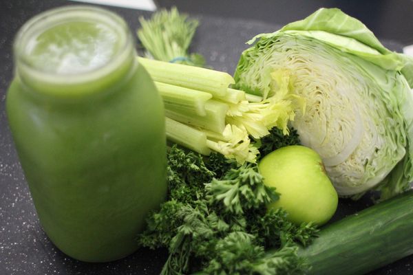 Zielone warzywa leżą na stole obok słoika z zielonym warzywnym smoothie.