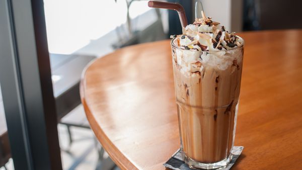Iced coffee in a tall glass with whipped cream and sauce