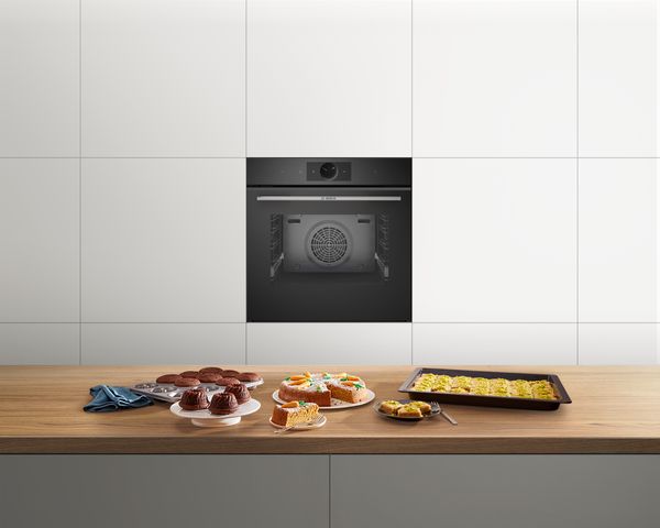 Forno da incasso nero integrato in una cucina moderna con dolci e pasticcini sul piano di lavoro