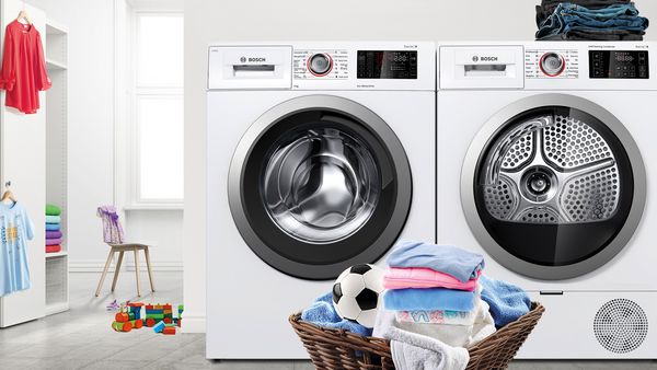 Bosch Wärmepumpentrockner und Waschmaschine in einer weißen Waschküche mit Wäschekorb und Kleiderschrank