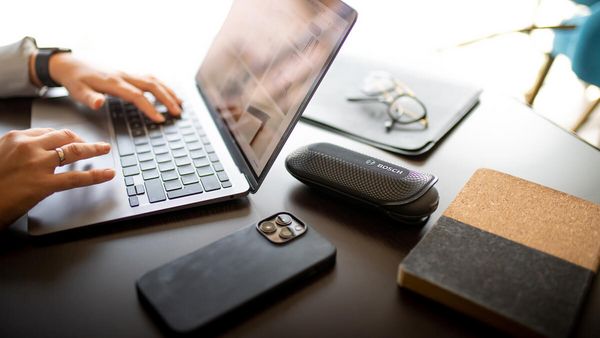 Le rafraîchisseur de textile FreshUp est posé sur un bureau avec un ordinateur portable et des fournitures de bureau.