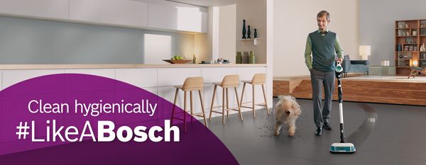 Bourgeois man vacuums and mops his living room floor very thoroughly with a Bosch Unlimited 7 ProHygienic Aqua.