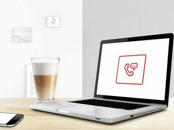 Laptop och smartphone på ett träbord med meddelande- och samtalsikoner, bredvid en latte och ett ljust fönster 